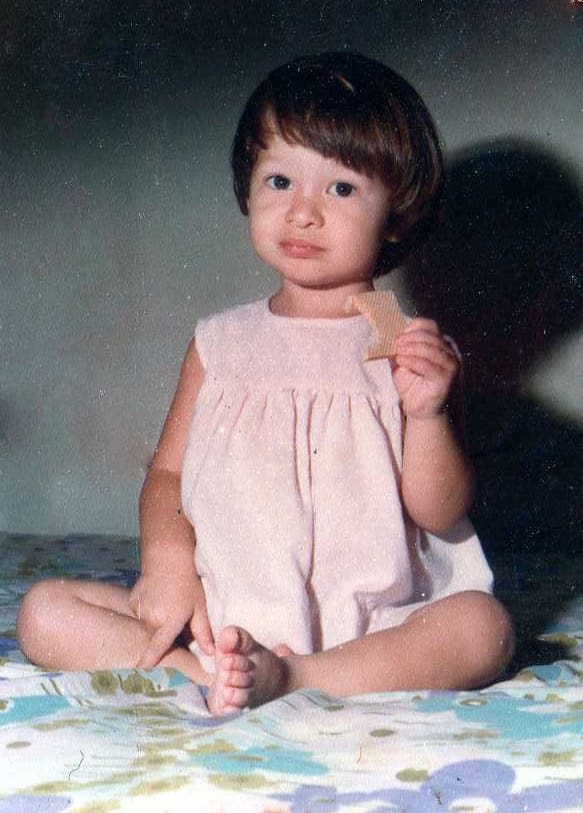Childhood photo of Wendy sitting indoors in Venezuela